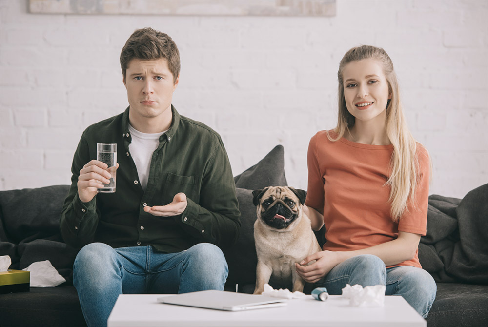 annoyed guy on couch next to dog